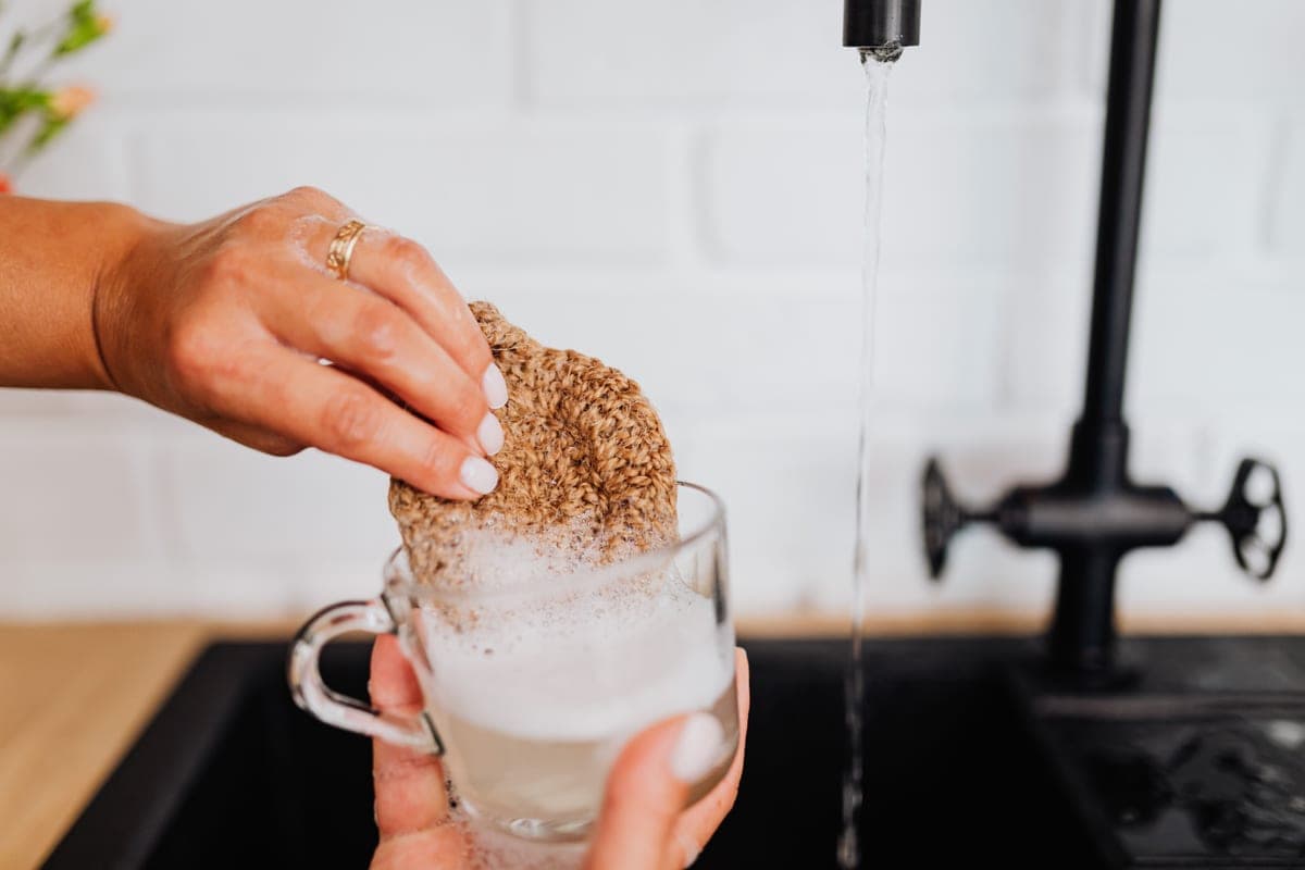 A glass jar being washed in soapy water